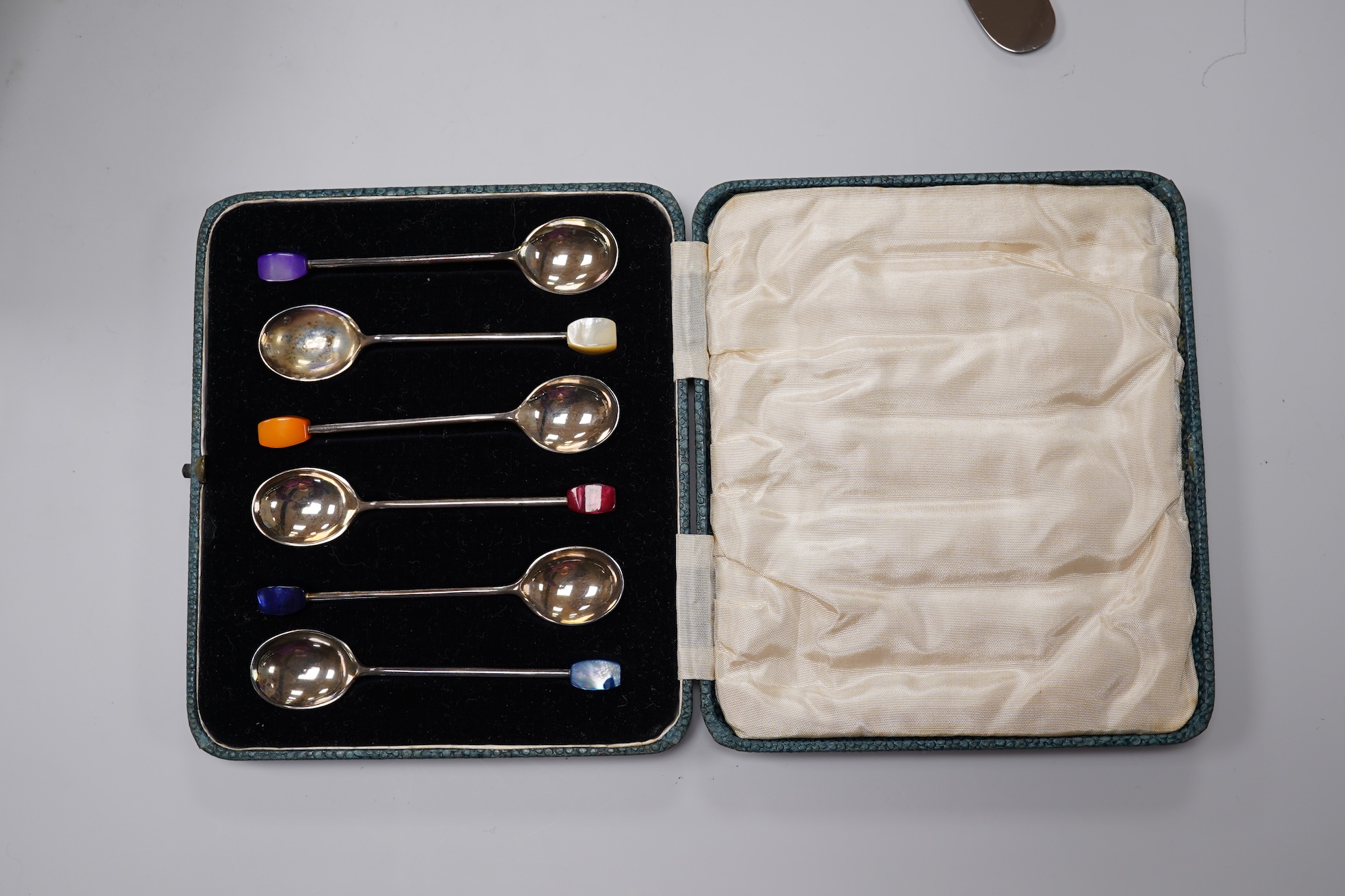 A George V silver Corinthian column candlestick, Birmingham, 1913, 16.1cm, a cased set of silver silver coffee spoons, two cased plated sets and a silver handled steel butter knife.